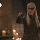 The one-eyed Aemond Targaryen raises a goblet and toasts his nephews in candelight.